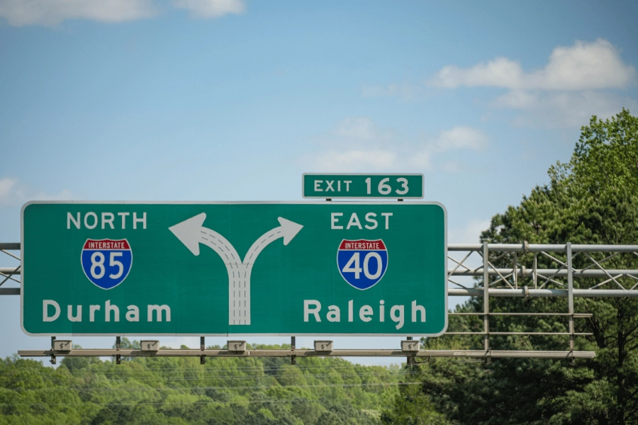 Green sign on the highway that points left towards Durham, NC and right towards Raleigh, NC